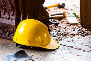 A yellow hardhat sits on the ground next to a carved wooden column.